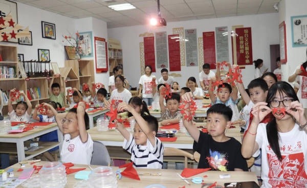 实践团成员与孩子们共同创作剪纸作品。beat365在线体育官网登录入口美术学院供图